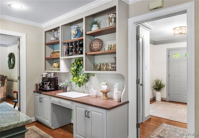 interior space with crown molding, baseboards, built in desk, and wood finished floors