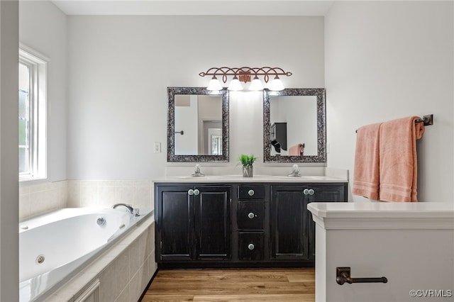 bathroom featuring a jetted tub, a sink, wood finished floors, and double vanity