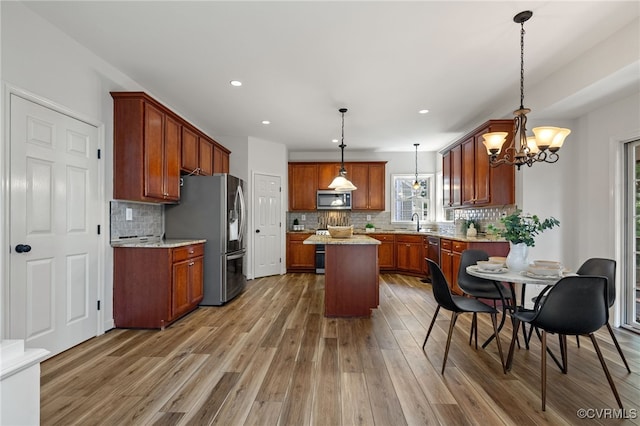 kitchen featuring stainless steel appliances, decorative backsplash, a sink, and light wood-type flooring