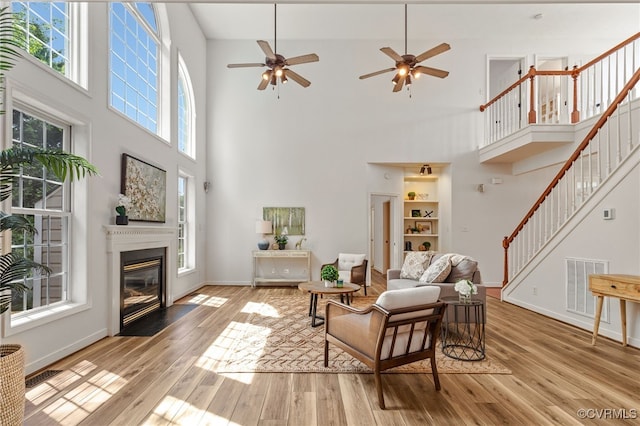 living room with a high ceiling, stairs, wood finished floors, and visible vents