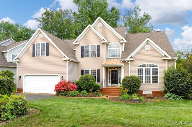 traditional-style house with roof with shingles, a front yard, driveway, and a garage