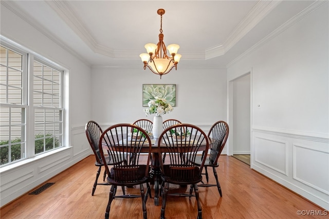 dining area featuring ornamental molding, a notable chandelier, light wood finished floors, and visible vents