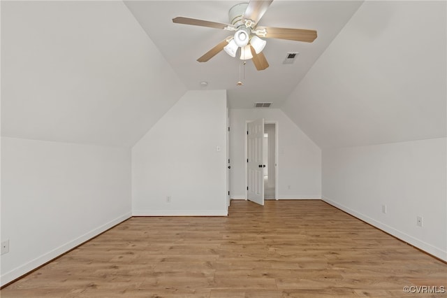 additional living space with baseboards, vaulted ceiling, light wood-type flooring, and visible vents
