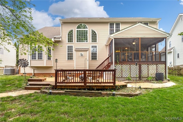 back of property with a yard, a wooden deck, a sunroom, and central air condition unit