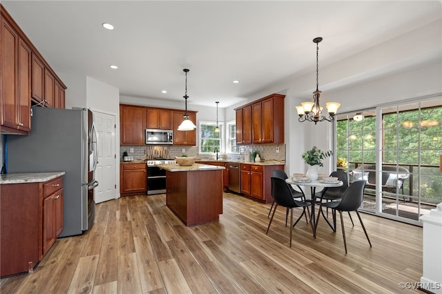 kitchen with a center island, decorative backsplash, light wood finished floors, and stainless steel appliances