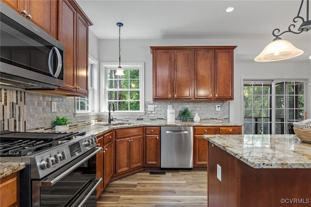 kitchen with a sink, appliances with stainless steel finishes, plenty of natural light, and light wood finished floors