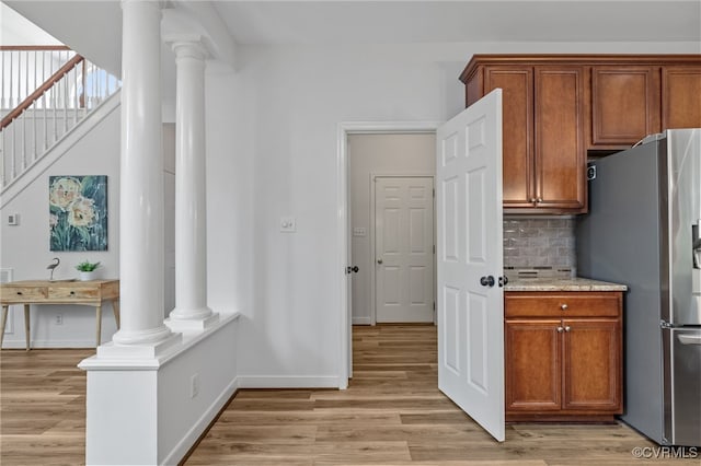 kitchen featuring ornate columns, brown cabinets, freestanding refrigerator, and light wood-type flooring