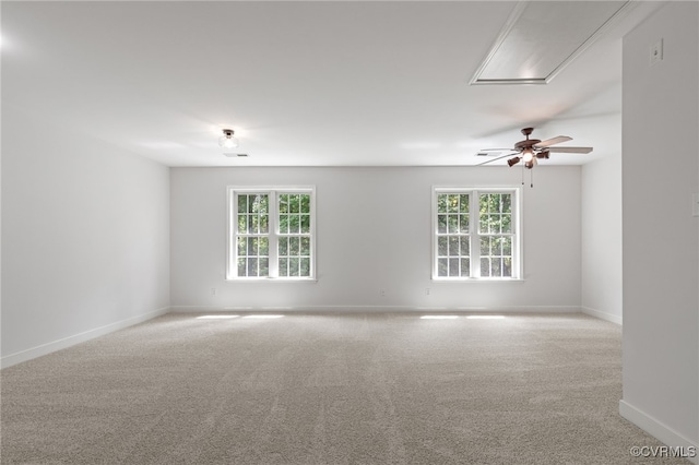 carpeted spare room featuring baseboards, plenty of natural light, attic access, and ceiling fan