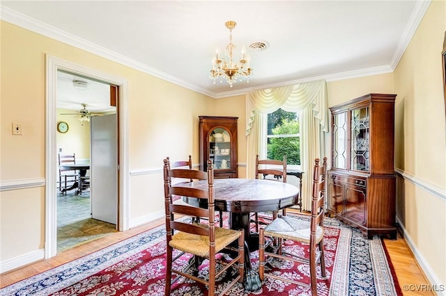 dining area featuring crown molding, baseboards, a chandelier, and light wood-style flooring