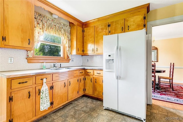 kitchen featuring light countertops, ornamental molding, white refrigerator with ice dispenser, and stone finish flooring
