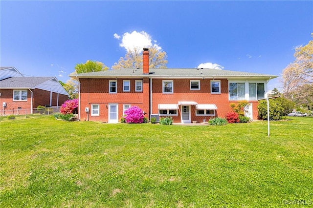back of house featuring a yard, brick siding, fence, and a chimney