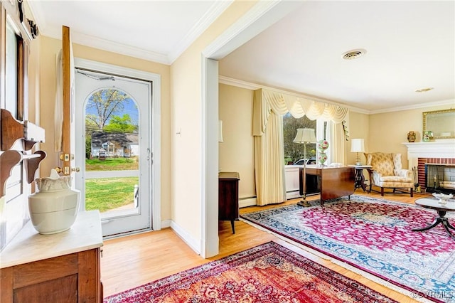 foyer with light wood-style floors, ornamental molding, plenty of natural light, and a baseboard heating unit