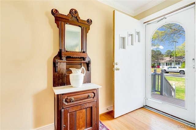 entryway with crown molding and light wood-style floors