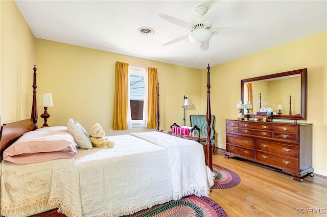 bedroom featuring baseboards, a ceiling fan, wood finished floors, and visible vents