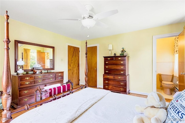 bedroom with baseboards, ensuite bathroom, ceiling fan, and wood finished floors