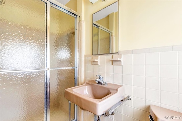 bathroom with a sink, tile walls, and a stall shower