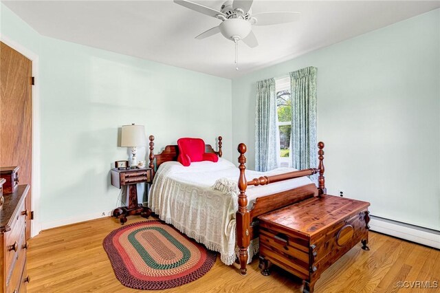 bedroom featuring baseboard heating, baseboards, a ceiling fan, and light wood-style flooring