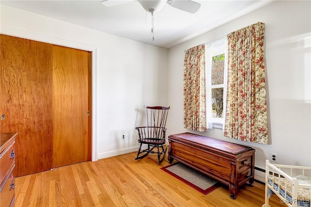 living area featuring baseboards, a ceiling fan, and light wood finished floors