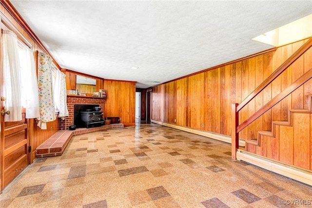 unfurnished living room featuring light floors, wooden walls, stairway, and baseboard heating