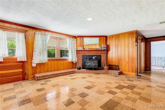 unfurnished living room featuring crown molding, a textured ceiling, wood walls, baseboards, and stairway