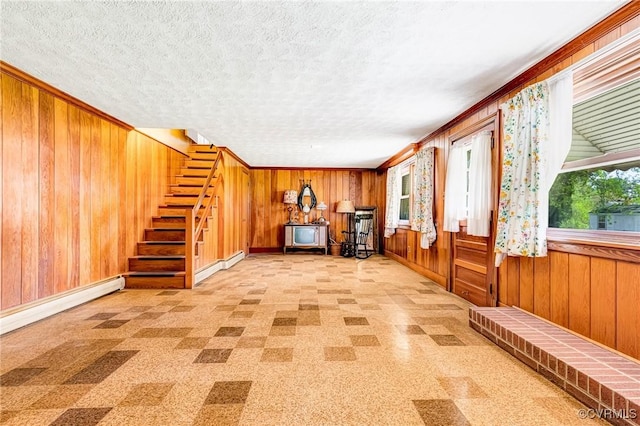 unfurnished room with a healthy amount of sunlight, ornamental molding, wooden walls, and a textured ceiling