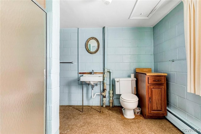 bathroom with a baseboard radiator, a sink, toilet, and tile walls