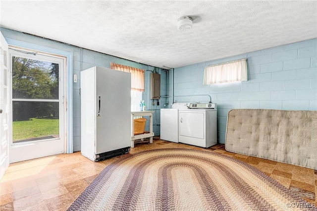 laundry room with independent washer and dryer, concrete block wall, a textured ceiling, and light floors