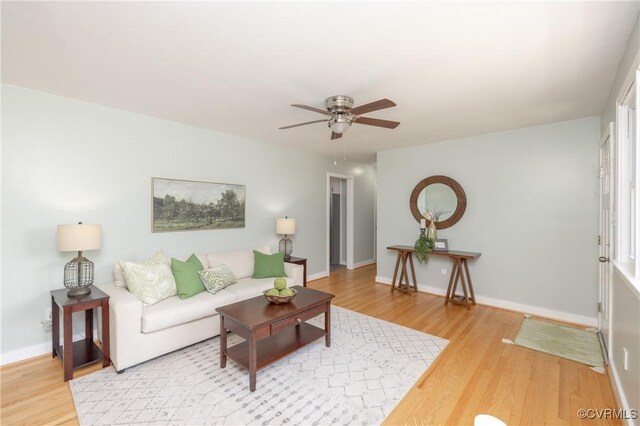 living area featuring baseboards, a ceiling fan, and wood finished floors