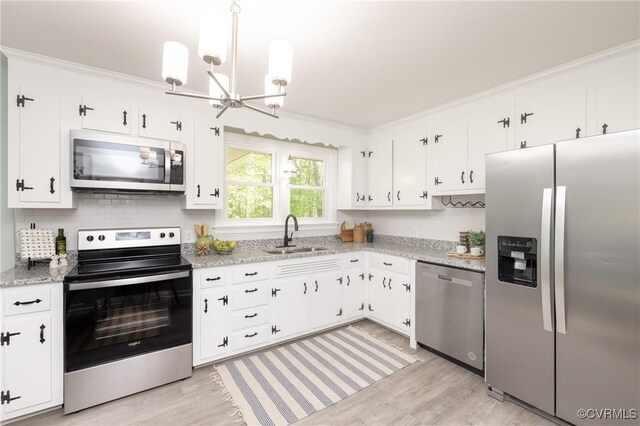 kitchen with light wood-style floors, tasteful backsplash, a sink, appliances with stainless steel finishes, and a notable chandelier