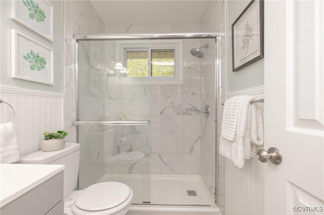 full bathroom with a marble finish shower, vanity, and toilet