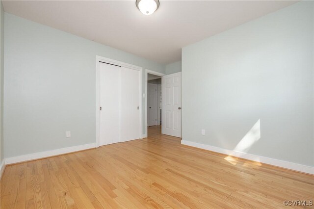 unfurnished bedroom with baseboards, wood finished floors, and a closet
