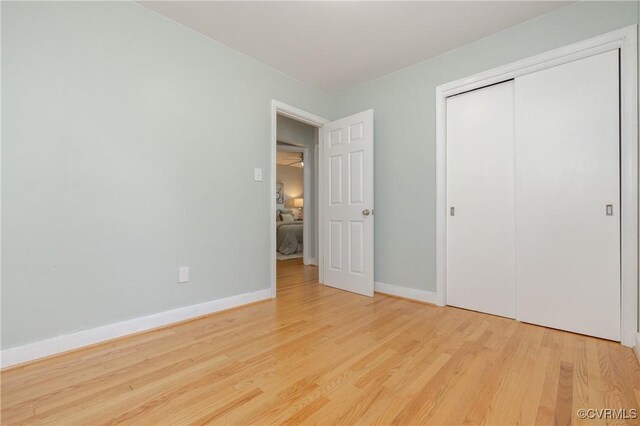 unfurnished bedroom featuring baseboards, wood finished floors, and a closet