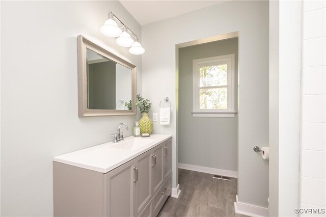 bathroom featuring vanity, baseboards, wood finished floors, and visible vents