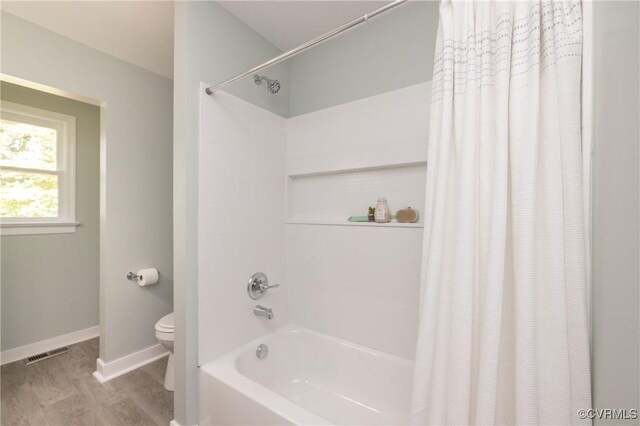 bathroom featuring shower / bath combination with curtain, visible vents, wood finished floors, baseboards, and toilet