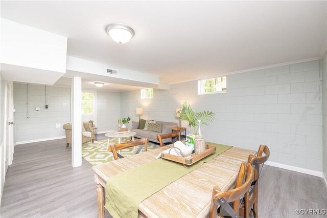 dining room featuring concrete block wall, visible vents, plenty of natural light, and wood finished floors