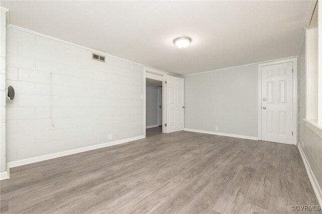 spare room with visible vents, ornamental molding, baseboards, and wood finished floors