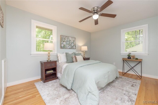 bedroom with baseboards, multiple windows, light wood finished floors, and ceiling fan