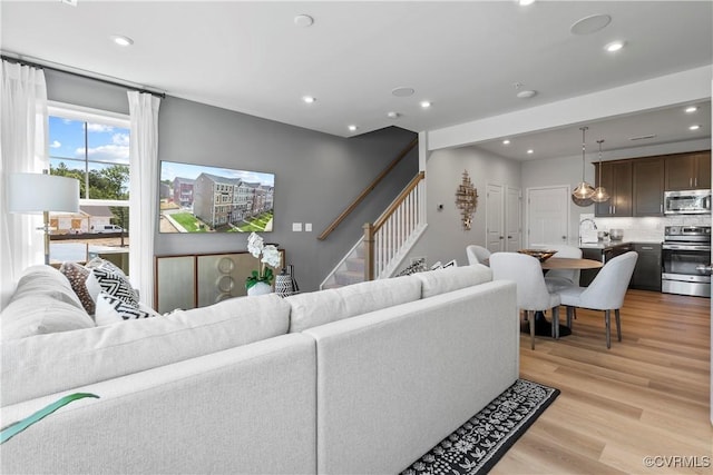 living room with light wood-type flooring, recessed lighting, and stairway