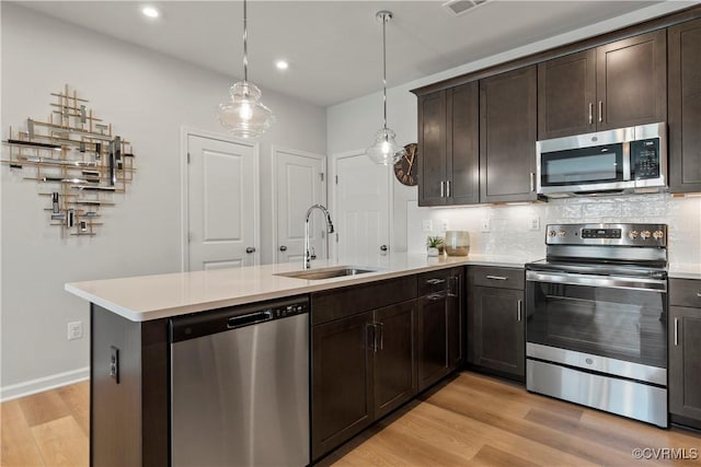 kitchen featuring a sink, appliances with stainless steel finishes, light wood-type flooring, and light countertops
