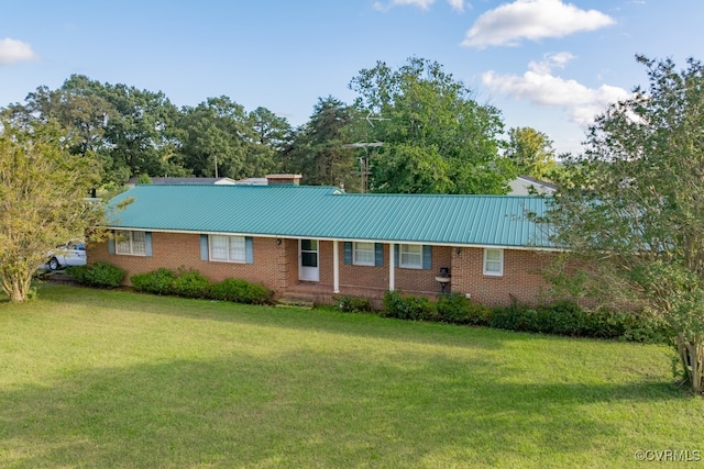 ranch-style home with brick siding, a front yard, and metal roof