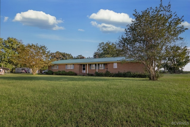 ranch-style home featuring brick siding, metal roof, a chimney, and a front lawn