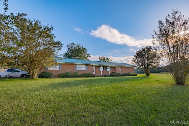 ranch-style house with brick siding, a chimney, and a front lawn