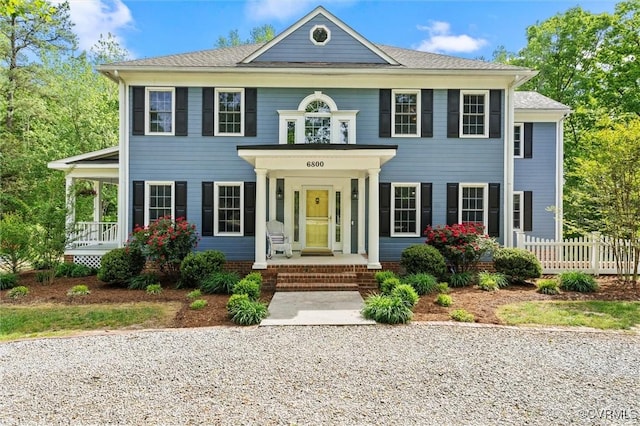 colonial home featuring a porch and fence