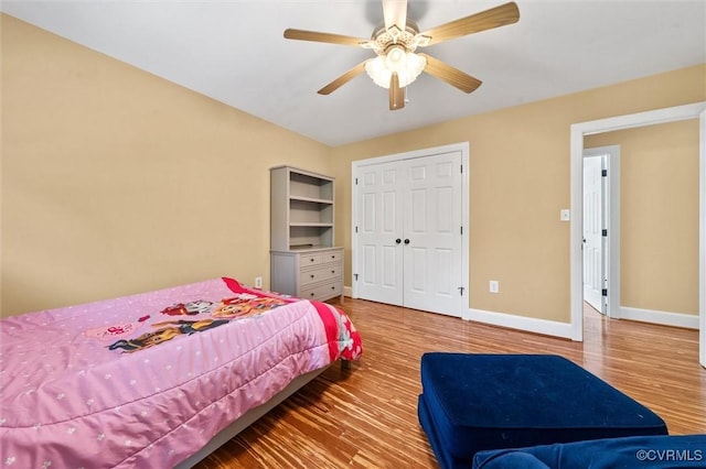 bedroom featuring baseboards, ceiling fan, wood finished floors, and a closet