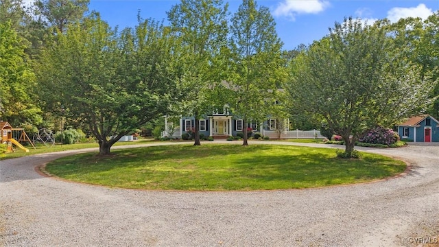 view of front of home with curved driveway, a front lawn, and playground community