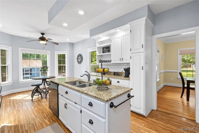 kitchen featuring open shelves, a sink, light wood-style flooring, black dishwasher, and tasteful backsplash