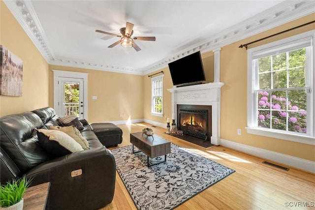 living room with ceiling fan, baseboards, a fireplace with flush hearth, wood finished floors, and visible vents