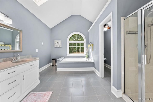 bathroom featuring vaulted ceiling with skylight, vanity, baseboards, and a shower stall