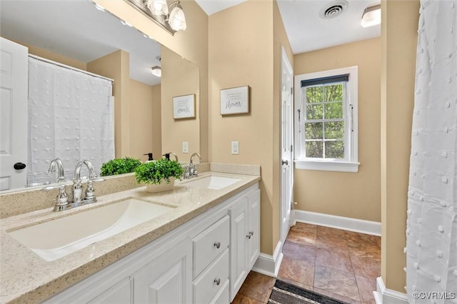 bathroom with visible vents, a sink, baseboards, and double vanity