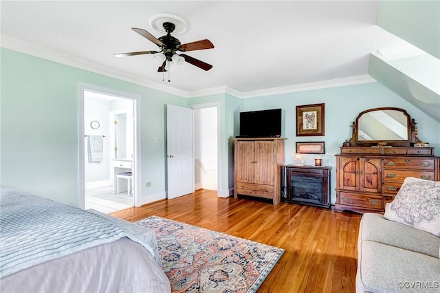 bedroom with crown molding, ensuite bathroom, a ceiling fan, and wood finished floors